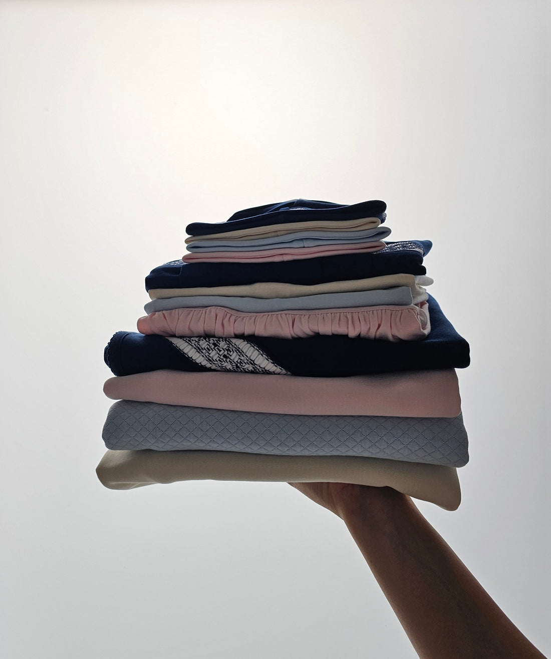 Stack of folded newborn baby clothes in soft neutral colors