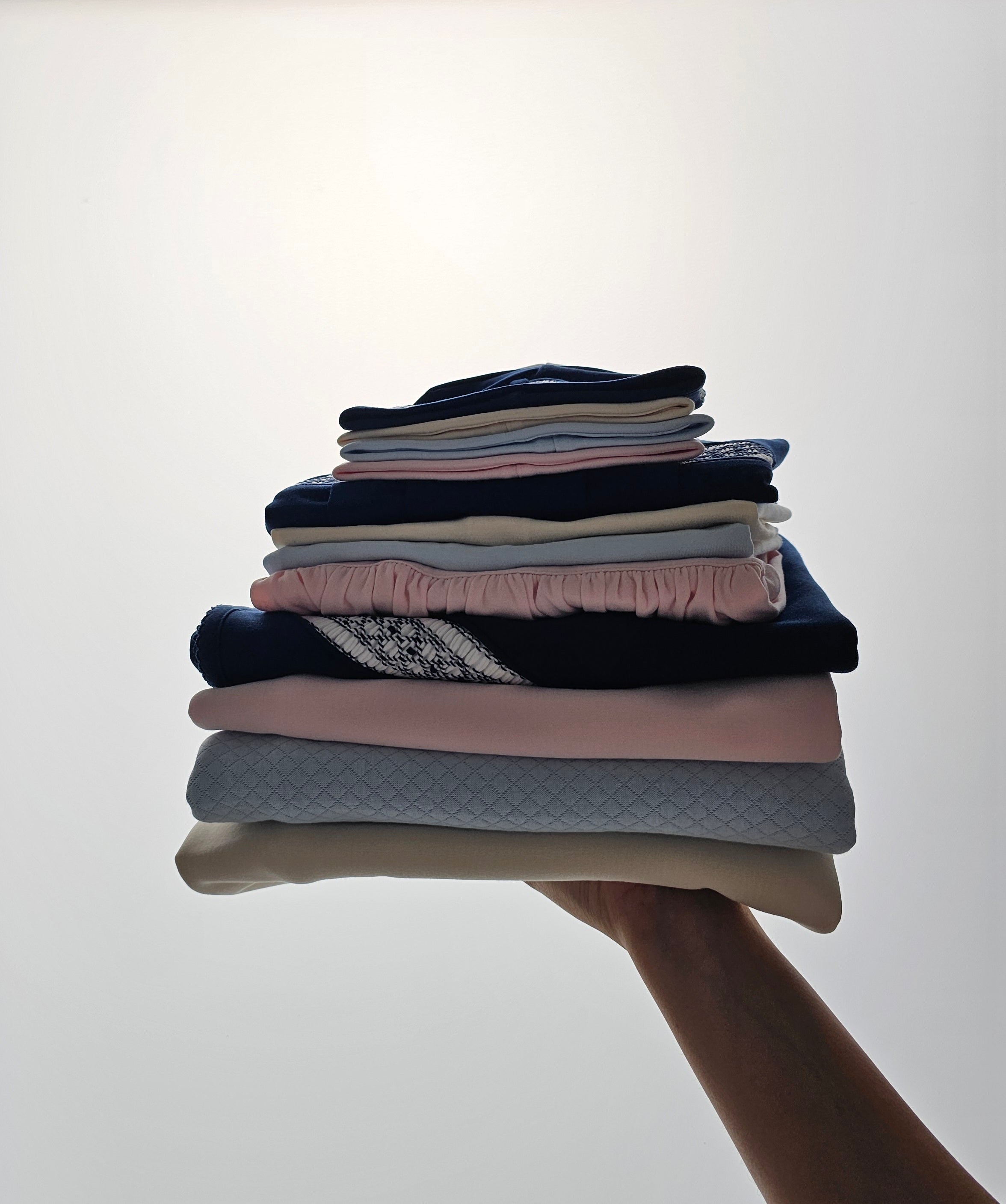 Stack of folded newborn baby clothes in soft neutral colors