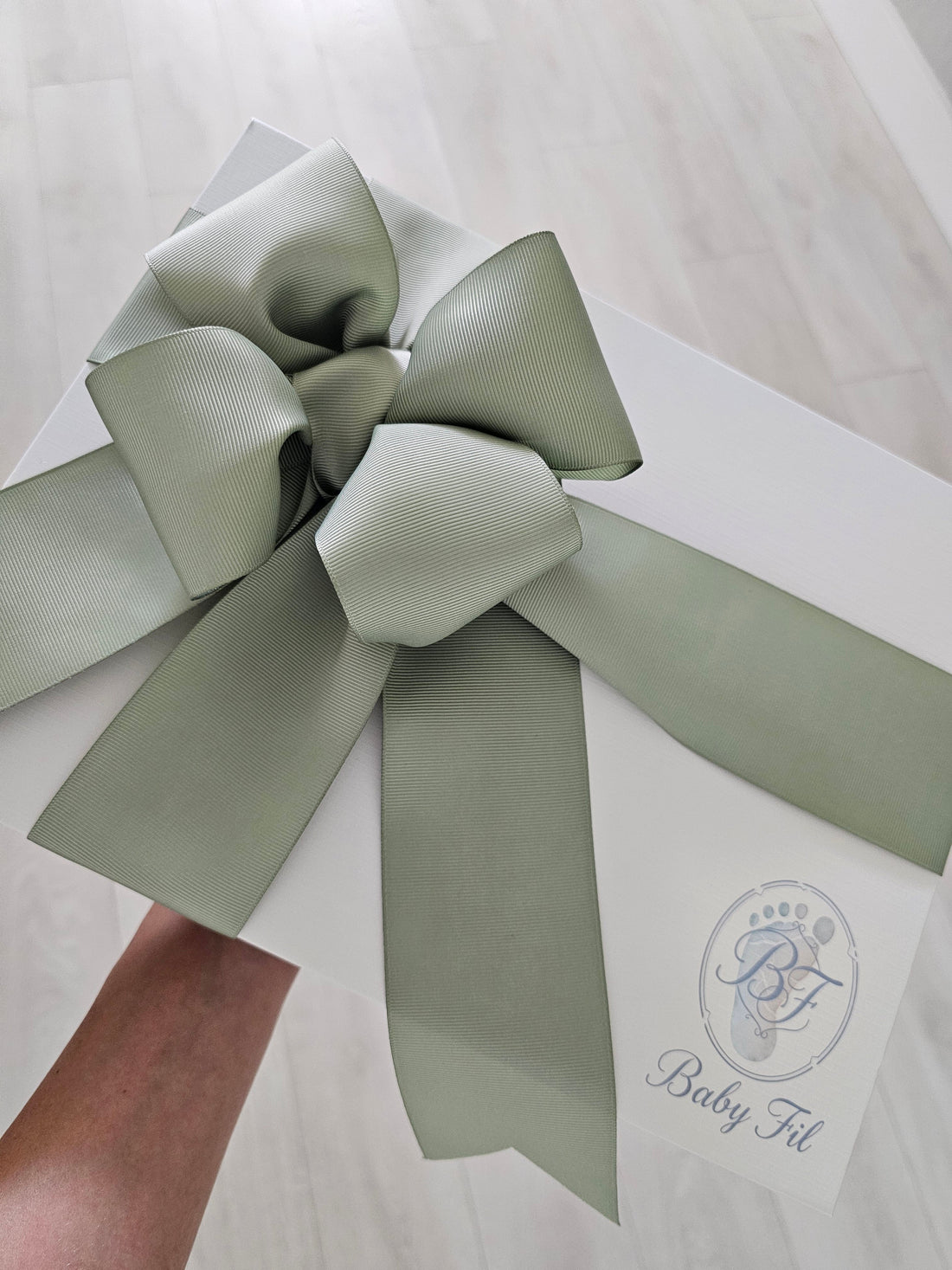 Elegant Baby Fil newborn gift box with a hand-tied sage green ribbon, perfect for baby shower gifts and coming home outfit..