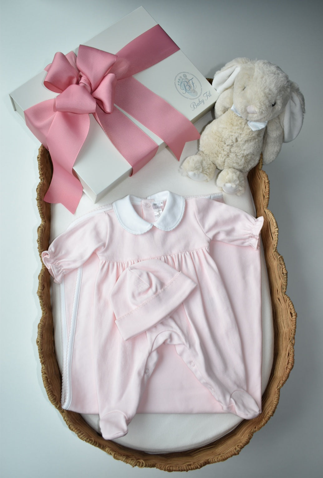 Pink newborn footie and blanket displayed beside a Baby Fil gift box with a decorative plush bunny