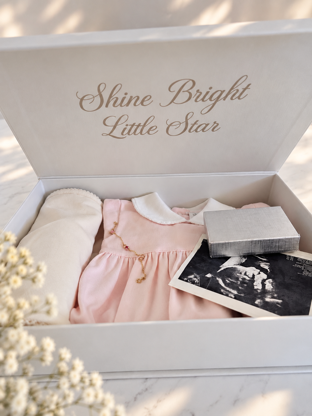 Baby Fil newborn gift box reused as a baby keepsake box, holding a first outfit, baby blanket, ultrasound photo, and special memories.